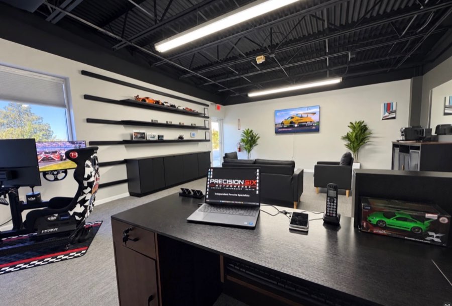 Wide view of the lobby from the front desk, with the racing simulator, lounge seating, and a TV on the back wall