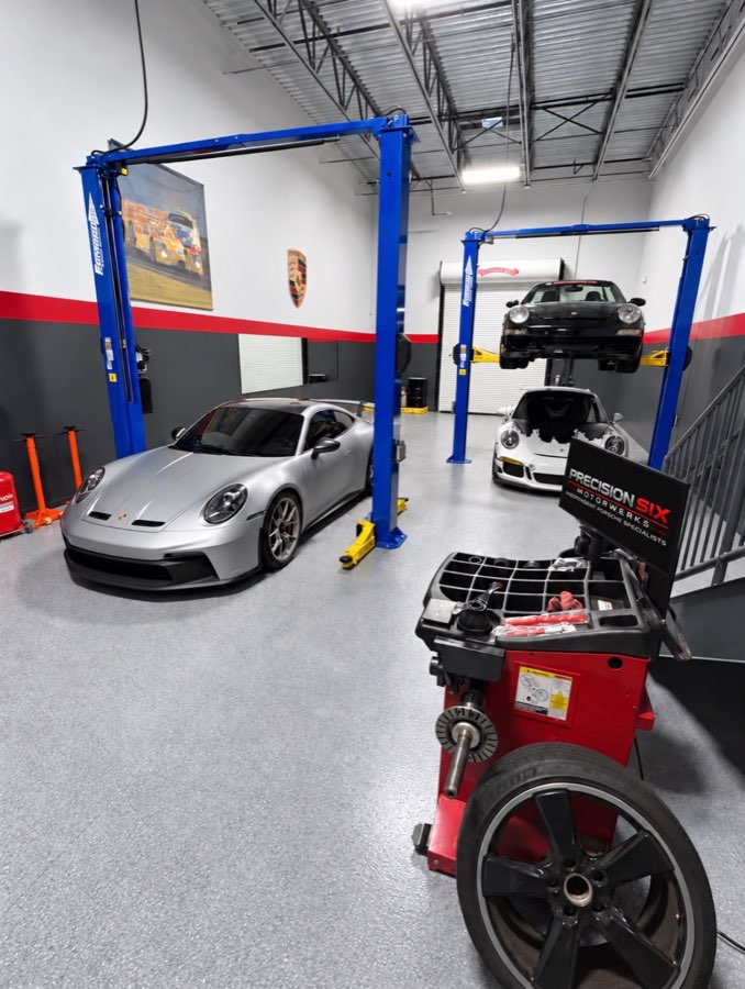 Silver 911 GT3 beside the tire machine, with a 911 raised on a lift behind it
