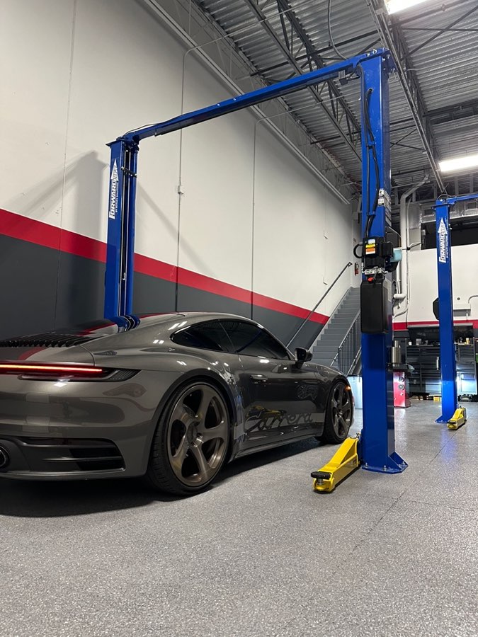 Grey 911 Carrera parked under a blue two post lift