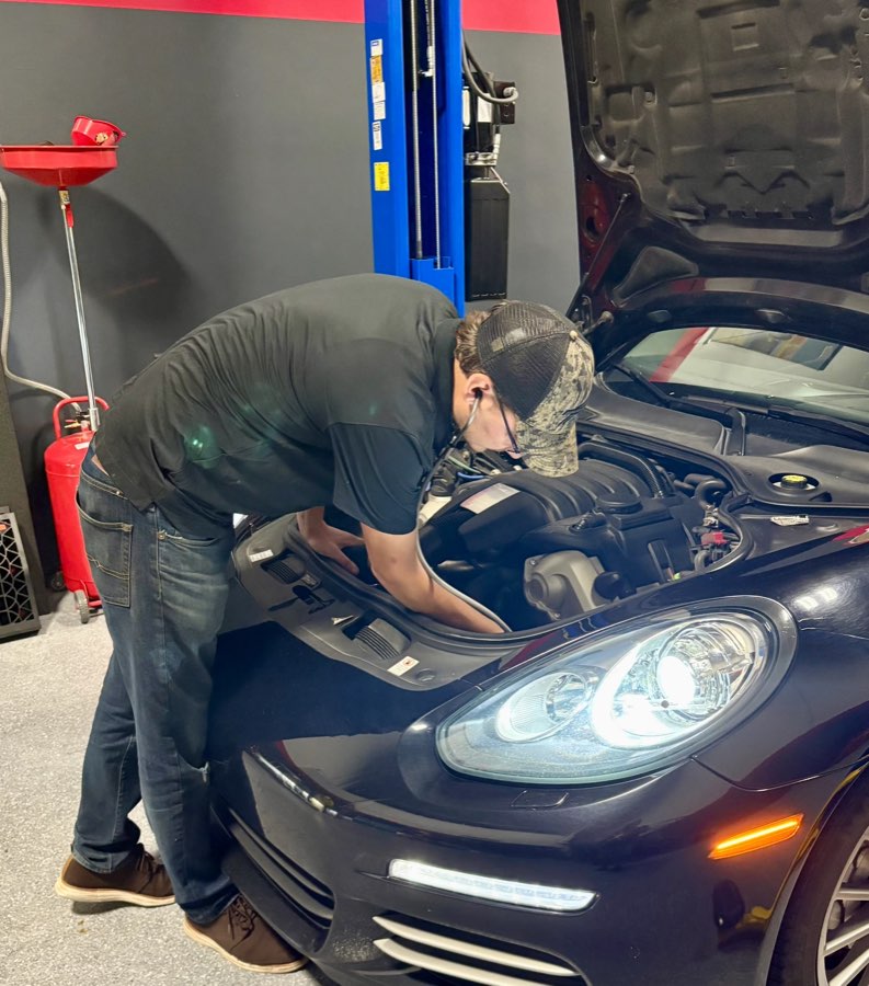 Technician using a mechanic's stethoscope to listen to the engine of a black Panamera